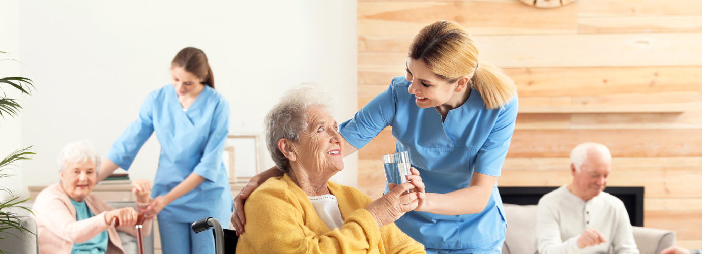 caregiver offering a glass of water to a senior woman
